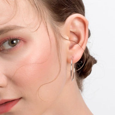 Side profile view of model wearing small sterling silver hoop earrings. 